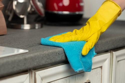 Gloved hand wiping down a kitchen countertop